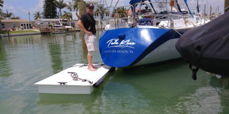 Vinyl boat name installed on blue hull with floating work platform in Madeira Beach FL